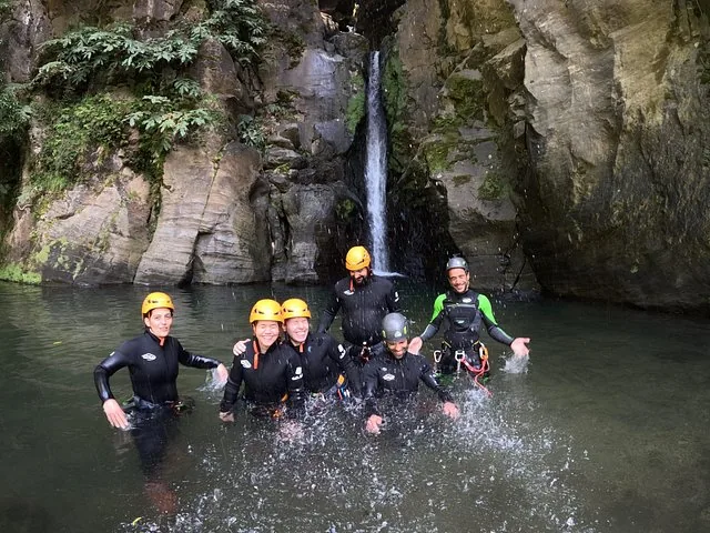 Group of people in wetsuits splashing and smiling in a pool