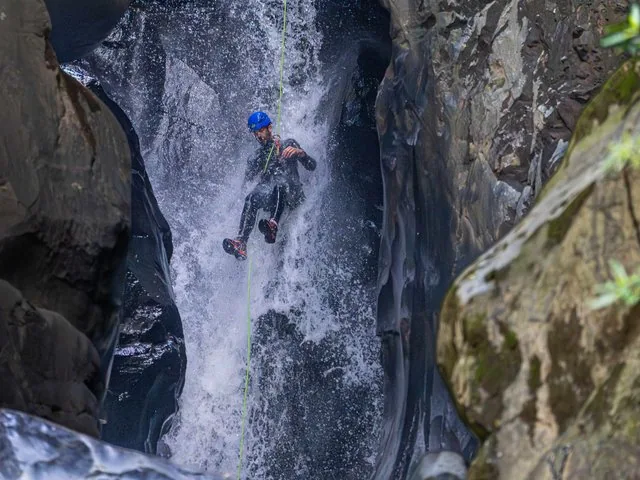 Personne descendant en rappel le long d'une cascade puissante dans une gorge rocheuse