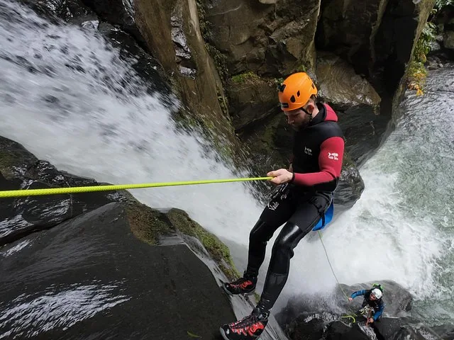 Personne en rappel le long d’une falaise rocheuse près d’une grande cascade