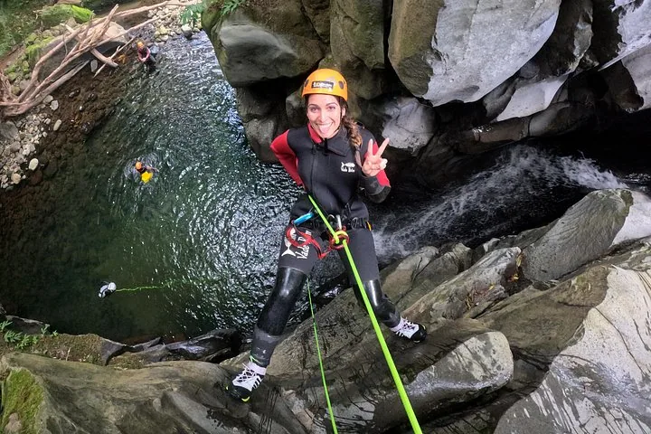 Person beim Abseilen an einer steilen, moosbewachsenen Felswand in einer Schlucht
