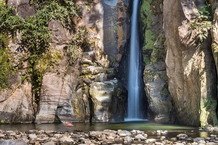 Hoher, schmaler Wasserfall, der in ein felsiges, von Klippen umgebenes Becken stürzt
